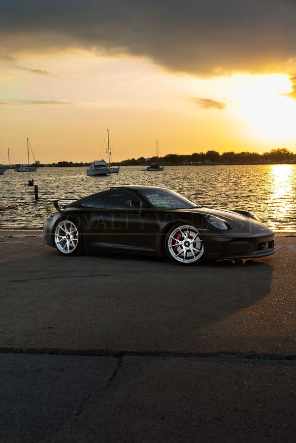 Front three-quarter of the GT3 at golden hour, boats on the bay