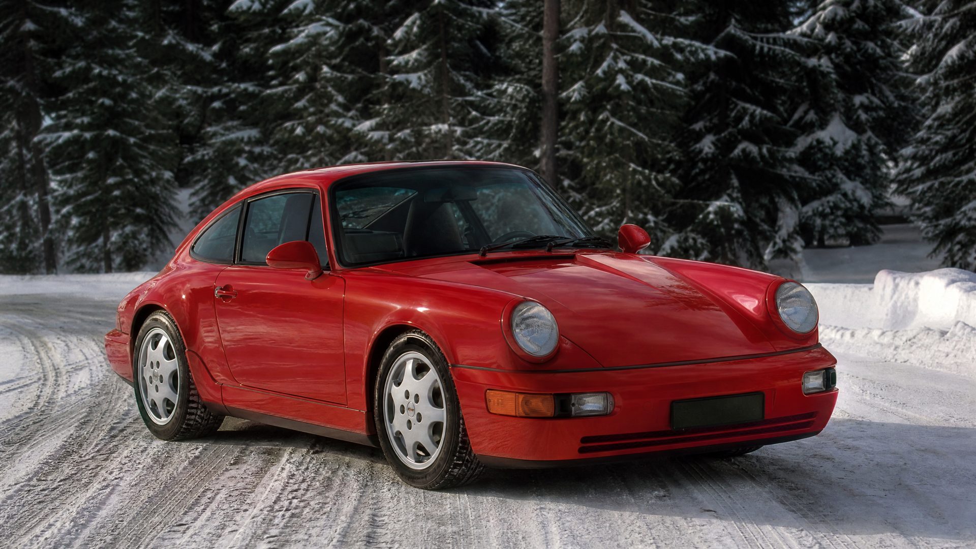 1989 photograph of a Guards red Porsche 911 Carrera 4 (964) beside a snowy forest road
