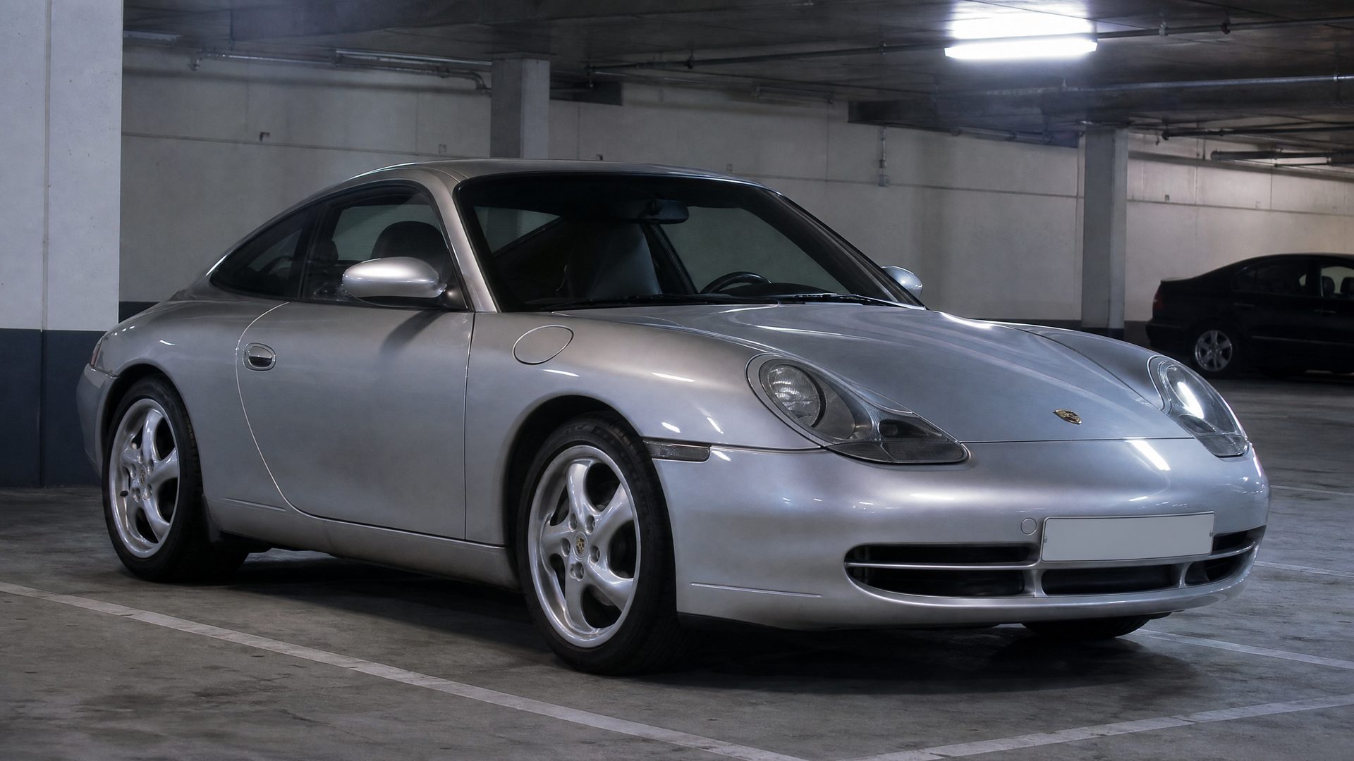 Late-1990s photograph of a silver Porsche 911 Carrera (996) with teardrop headlights in an underground car park