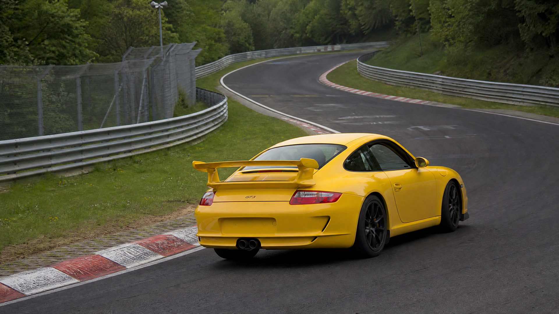 Mid-2000s photograph of a yellow Porsche 911 GT3 (997) with fixed rear wing on the Nürburgring Nordschleife