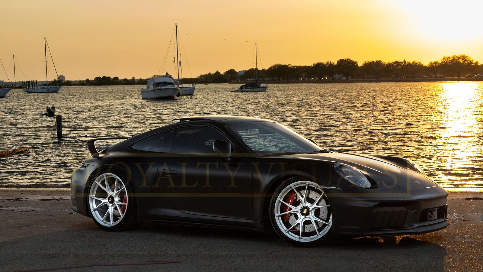 Pri’s satin-black 2026 Porsche 911 GT3 (992.2), plate 26911, side profile at golden hour on the Davis Islands waterfront, Tampa